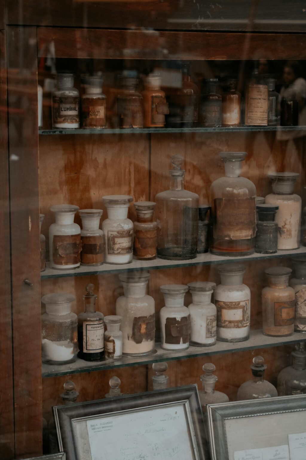 A collection of vintage apothecary bottles displayed in an antique wooden cabinet, showcasing rustic charm.