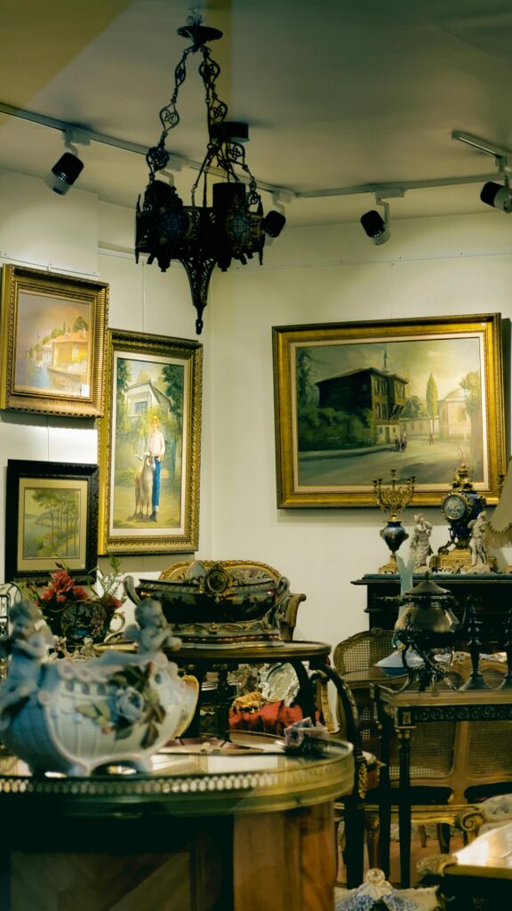 A beautifully decorated room with paintings, antique furniture, and a chandelier, creating a vintage interior design vibe.
