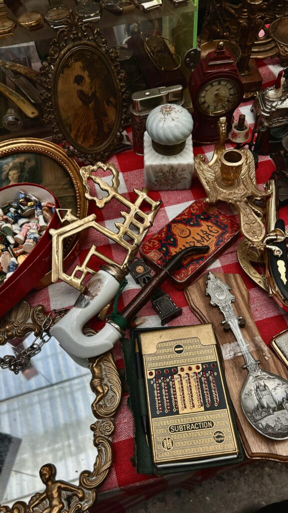 Assorted antique items displayed on a red checkered tablecloth at a market.